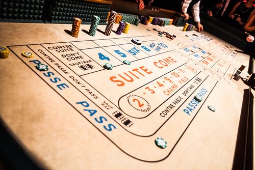 an image of Craps Table, Chips Piles and People Gambling all Around